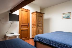 a bedroom with a bed and a wooden cabinet at Maison Studios & Appartements Les 4 Vents in Luc-sur-Mer