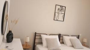a bed with white pillows and a picture on the wall at Venetton Garden House Corfu in Gouvia