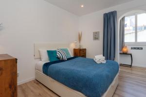 ein Schlafzimmer mit einem großen Bett mit einer blauen Decke in der Unterkunft Lush Botanic Oasis with a Boho Hideaway, Near Beach & Cafés in Lagos