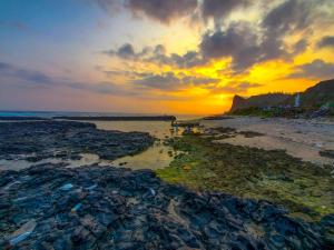 a sunset over a beach with rocks and a body of water at Khách Sạn Thu Thành in Ly Son +13 photos