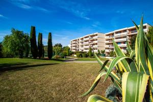 a building in a park with trees and a grass field at Eden Bleu, parking, piscine, tennis et soleil in Antibes