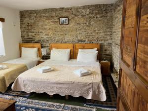 two beds in a room with brick walls at Guest House Salaria in Gjirokastër