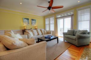 Una sala de estar con sofás y un ventilador de techo. en Salty Banana by Carolina Beach Realty, en Kure Beach