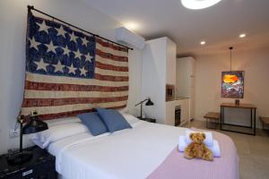 a teddy bear sitting on a bed with an american flag on it at Osito Hub - l'Explorador Andrés in Valencia