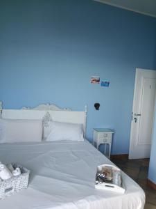 a bedroom with a white bed with a blue wall at Case Nereidi 2 in Porticello +12 photos