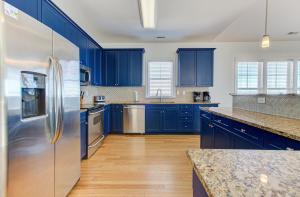 een blauwe keuken met roestvrijstalen apparatuur en blauwe kasten bij Sandstep by Carolina Beach Realty in Carolina Beach