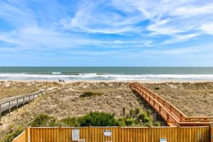 een houten hek op een strand met de oceaan bij Sandstep by Carolina Beach Realty in Carolina Beach