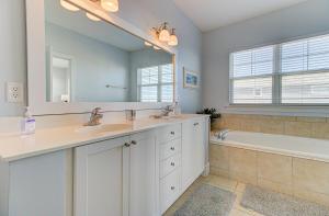 een badkamer met 2 wastafels, een bad en een spiegel bij Sandstep by Carolina Beach Realty in Carolina Beach +52 foto's