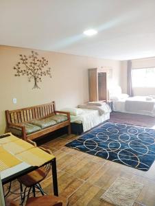 een kamer met 2 bedden, een bank en een tapijt bij Hospedaria Dona Clara in Tiradentes