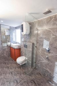 a bathroom with a toilet and a glass shower at White Castle Himalayan View by Lavender Hotels in Shimla