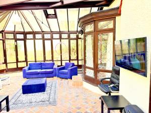 a living room with blue furniture in a conservatory at 304 Norbury House in Norbury