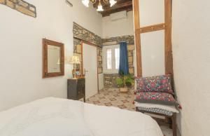 a bedroom with a bed and a chair and a mirror at Philoxenia traditional house in Pastida