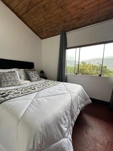 a bedroom with a white bed and a large window at Aconchego da Lapinha in Santana do Riacho