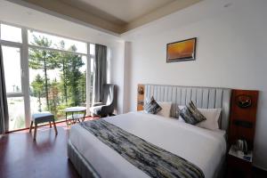 a hotel room with a bed and a large window at White Castle Himalayan View by Lavender Hotels in Shimla