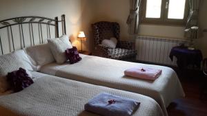 a bedroom with two beds with purple towels on them at La Trucha del Arco Iris in El Acebo de San Miguel