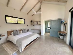 a bedroom with a bed and a desk and a window at Hillandale Huddle - modern forest cabin near Plett in Plettenberg Bay