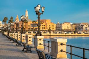 une rangée de bancs et de lampadaires à côté d'un plan d'eau dans l'établissement Mövenpick Hotel Bari, à Bari