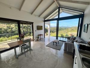 a living room with a table and a large window at Hillandale Huddle - modern forest cabin near Plett in Plettenberg Bay