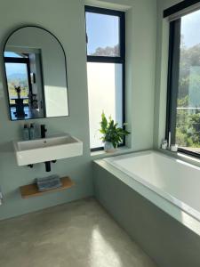 a bathroom with a tub and a sink and a mirror at Hillandale Huddle - modern forest cabin near Plett in Plettenberg Bay +33 photos
