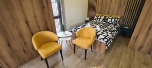 a bedroom with a bed and two yellow chairs at Studio Andrea in Divčibare