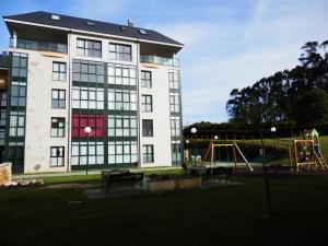 duży biały budynek z placem zabaw przed nim w obiekcie Apartamento Dicar w mieście Foz