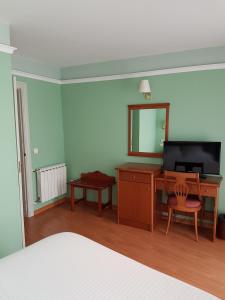 1 dormitorio con escritorio, TV y espejo en Hotel Faro de San Vicente, en San Vicente de la Barquera