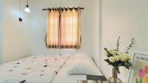 a bedroom with a bed and a vase of flowers at Bann Sawasdee Donmueng- Saimai หลังใหญ่ ฟรี wifi in Ban Sai Mai