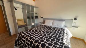 a bedroom with a bed with a black and white comforter at Luz del Rincón in Merlo