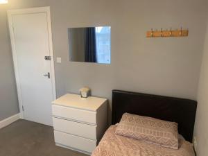 a bedroom with a bed and a dresser and a mirror at North London Room in Enfield Lock