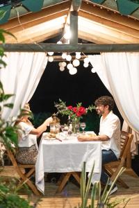 a man and woman sitting at a table under an umbrella at Levit Glamping - Hotel Guatapé Peñol in Guatapé +134 photos