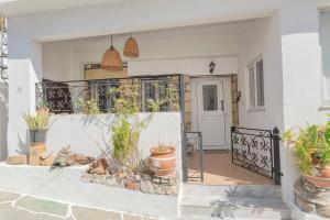 a white house with potted plants and a gate at Philoxenia traditional house in Pastida