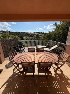 a wooden table and chairs on a patio at Appartement 2 chambres, mezzanine et piscine in Porto-Vecchio