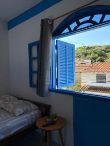 een slaapkamer met een raam met een bed en een tafel bij Kitnet Brava 2 in Búzios