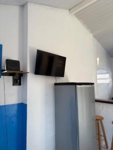 een flatscreen-tv aan de muur met een koelkast bij Kitnet Brava 2 in Búzios