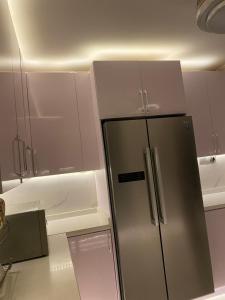 a stainless steel refrigerator in a kitchen with white cabinets at Bodija Suite Ibadan 3bedroom apartment in Ibadan