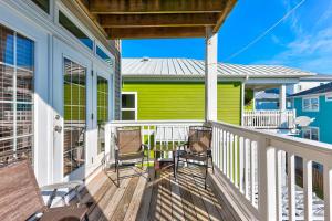 a porch with two chairs and a green house at Jacks Beach House by Carolina Beach Realty in Carolina Beach