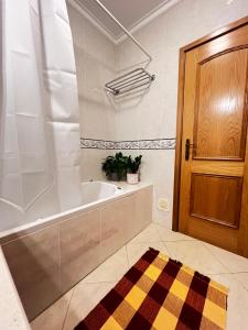 a bathroom with a bath tub and a wooden door at Ilumina Hostel Albufeira in Albufeira +24 photos