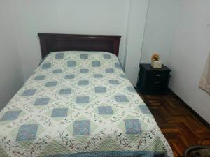 ein Bett mit einer Decke in einem Schlafzimmer in der Unterkunft Amplio y acogedor departamento in Loja