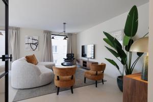 a living room with a couch and chairs and a tv at Savoye Plaza Suites Ostend - Casselbergh Residences in Ostend