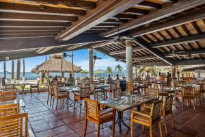 a restaurant on the beach with tables and chairs at Costa Sur All Inclusive Resort in Puerto Vallarta