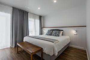 a bedroom with a large bed and a wooden bench at São Jorge Holiday Homes in Velas