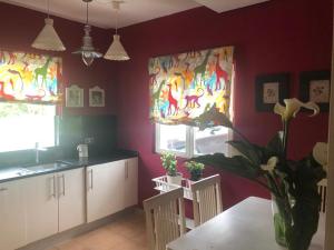 a kitchen with purple walls and windows with curtains at Villa Güezmes in Somo
