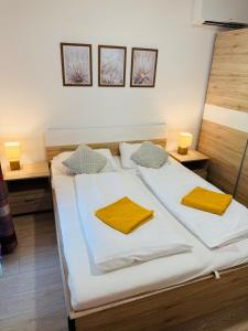 Schlafzimmer mit einem Bett mit weißer Bettwäsche und gelben Kissen in der Unterkunft Casa Romana 2 Siófok apartman in Siófok + 8 Fotos