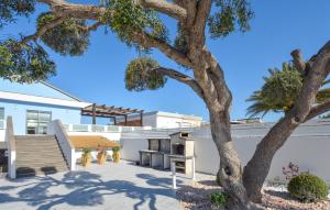 ein Baum und eine Bank vor einem Gebäude in der Unterkunft 4 Bedroom Amazing Home In Kaukana in Villaggio Azzurro