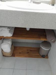 a bathroom with a sink and a shelf with towels at Appartement charmant à Grand-Bourg, 27 m², accès à la piscine. in Saint-Louis