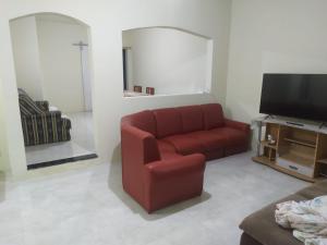a living room with a red couch and a television at Casa Praia com piscina Itanhaem in Itanhaém