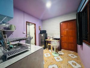a kitchen with purple walls and a table with a fan at Serenity House 4A in Ban Ko Khwan