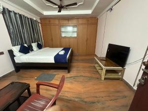 a bedroom with a bed and a tv and a chair at Hotel KP Suites Near RK Beach Vizag in Visakhapatnam