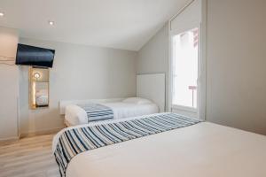 two beds in a white room with a window at Résidence ITXASOA - Appartements, plage d'Hendaye in Hendaye