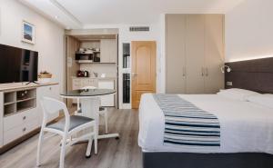 a bedroom with a bed and a table and a kitchen at Résidence ITXASOA - Appartements, plage d'Hendaye in Hendaye